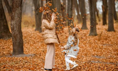 mujer y niña jugando con hojas 