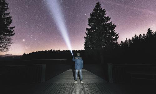 fotografía persona con linterna observando cielo