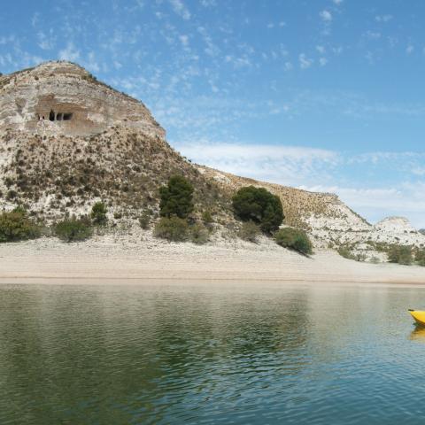 La Camareta. Navegando a los pies de un lugar mágico: la cueva de la Camareta. El eremitorio excavado en la roca se erige sobre las aguas del embalse de Camarillas, cerca de Agramón (Albacete). Detrás, la Sierra de los Donceles (declarada LIC y ZEPA).